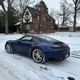 a blue 2023 porsche 911 carrera on a snow-covered road in michigan